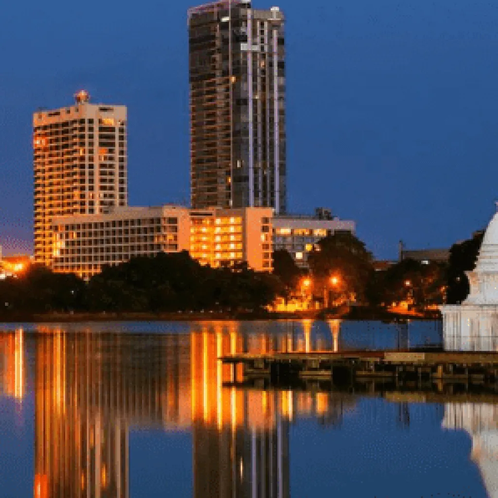 Colombo towers and a white stupa reflected in the lake at dusk