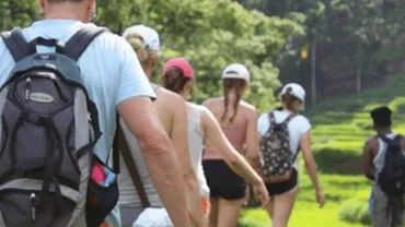 Hikers with backpacks walking along a green hillside path
