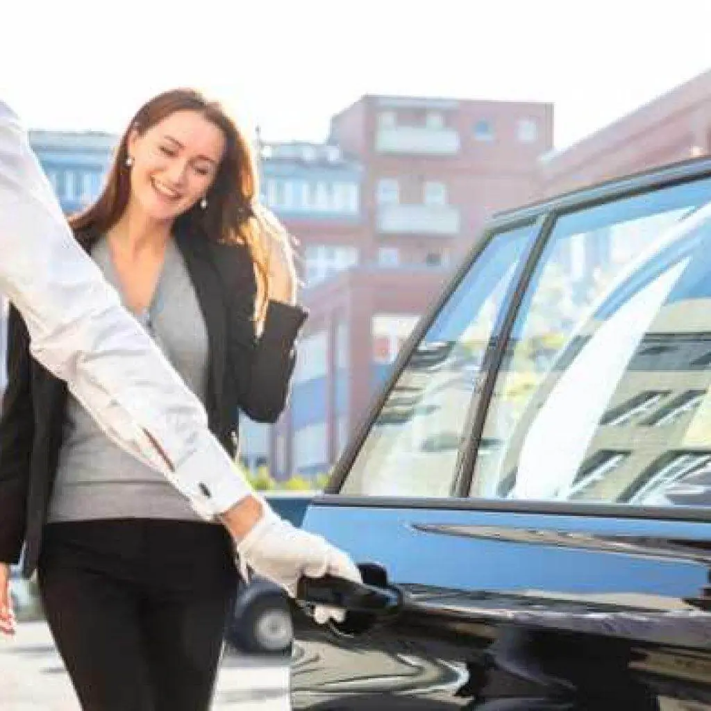 A chauffeur opening a car door for a smiling woman