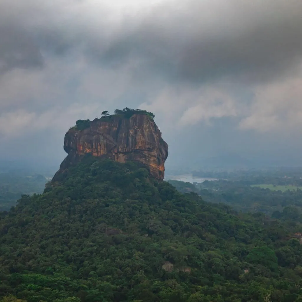 The Sigiriya rock rising above the jungle on a cloudy day, seen from Pidurangala