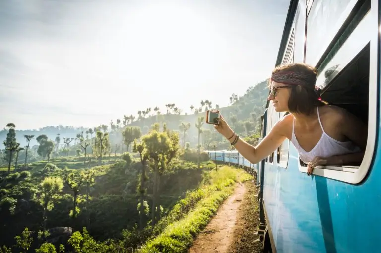 Traveler leaning out of a train above the tea fields of Sri Lanka