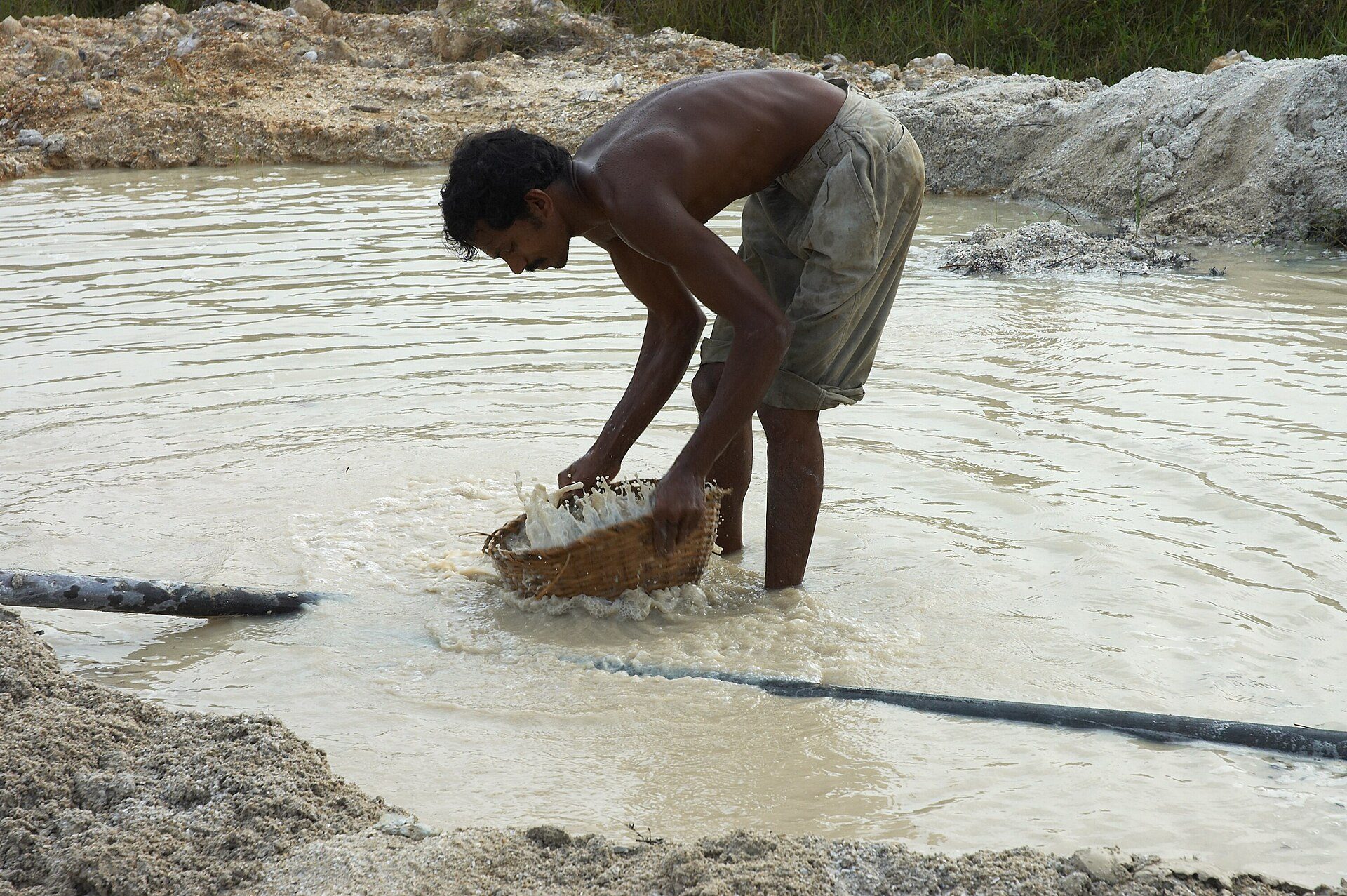 A miner washing gravel in a basket at a gem pit in southern Sri Lanka